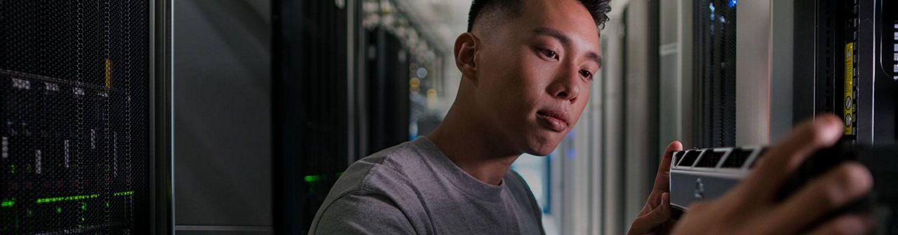 Focused technician inspecting equipment in a server room, associated with Micron's updated high-performance memory strategy