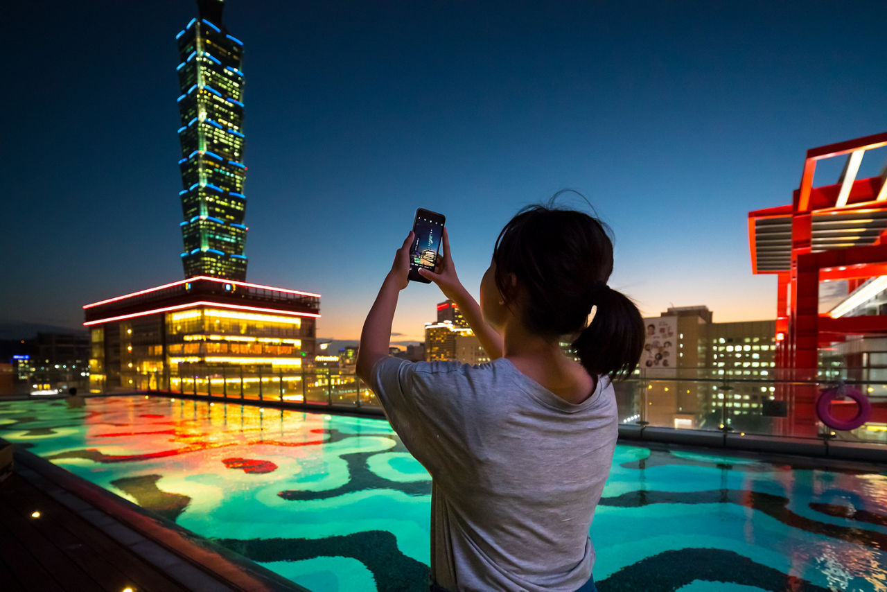 Girl taking picture of cityscape with smartphone