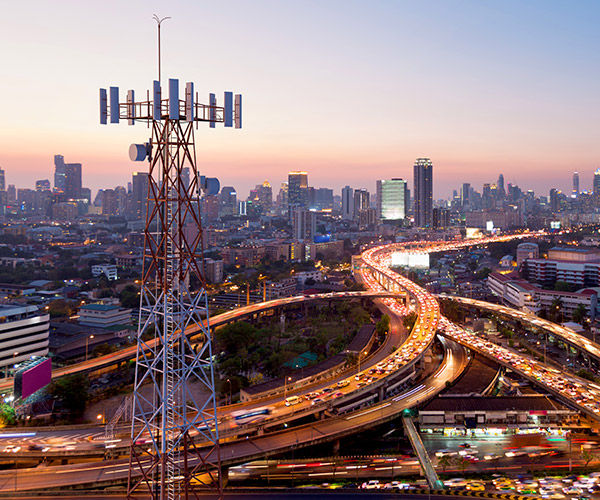 Large cityscape with cell tower and busy intersecting highways in the foreground.