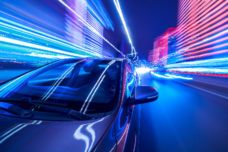 A car driving at high speed through a city street at night​