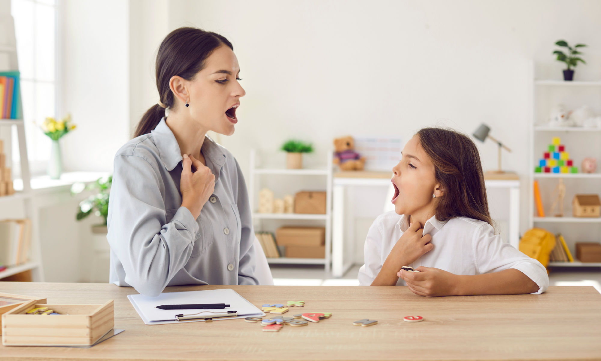 A woman helping a young girl with speech therapy