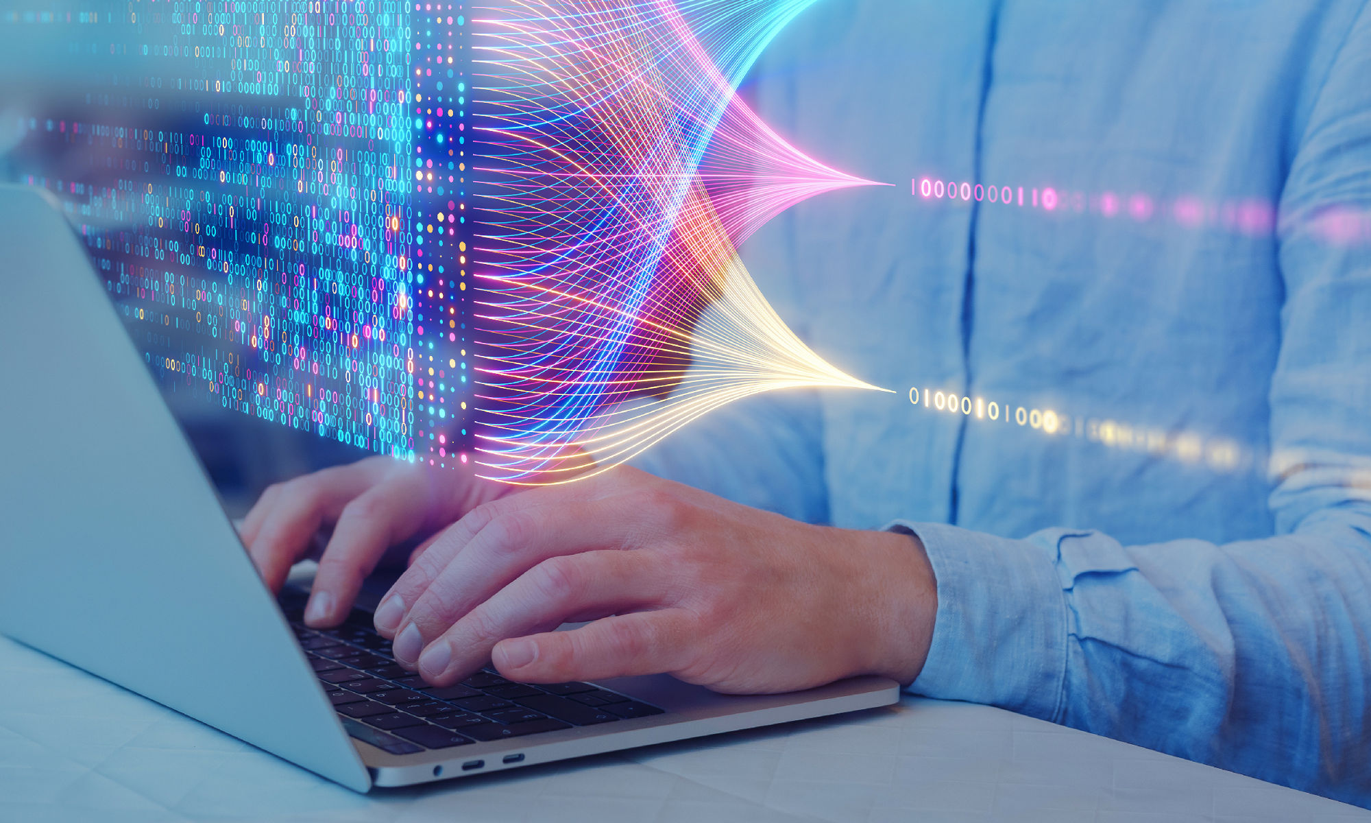 hands typing on a laptop illuminated in purple light