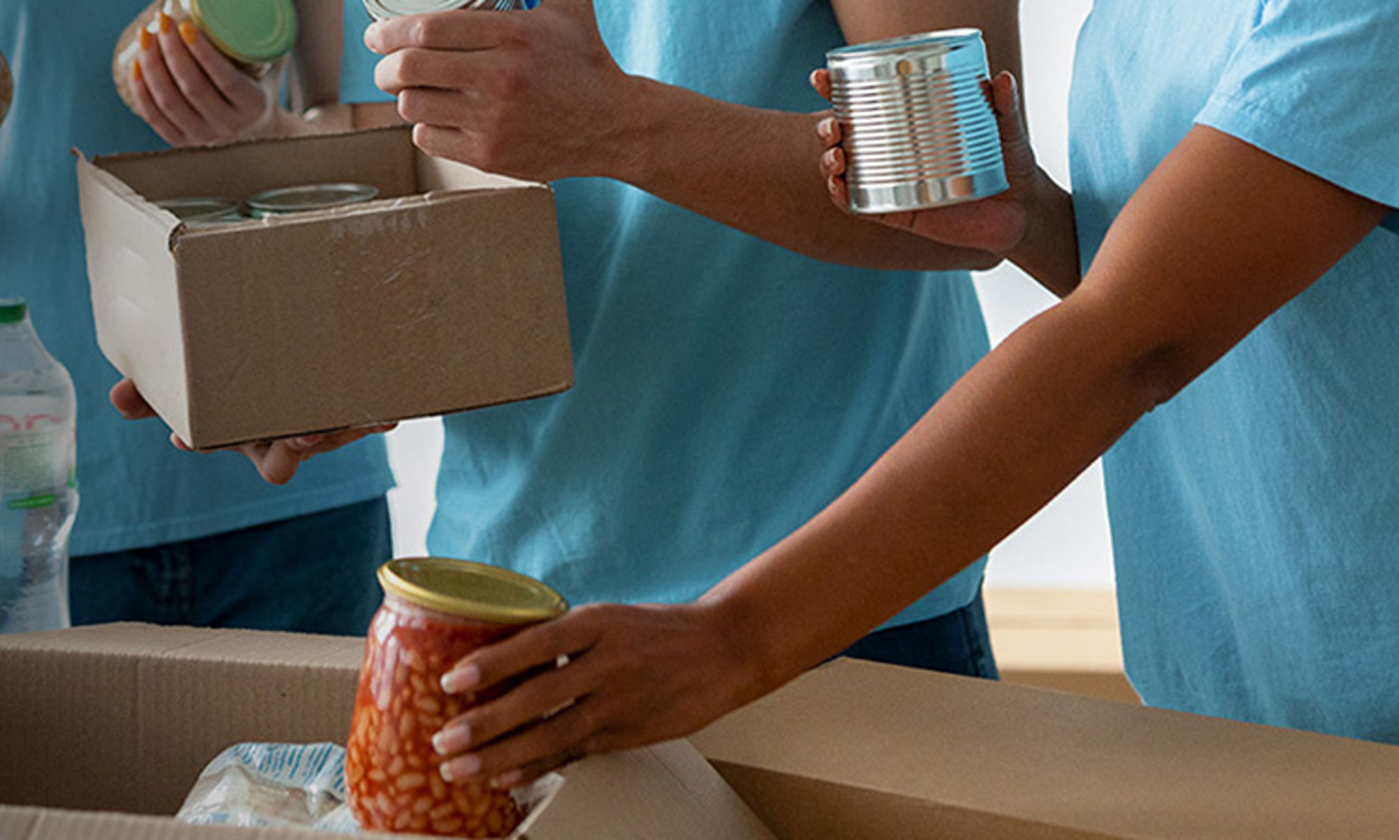 慈善団体への寄付用の食料品を箱に詰め込むボランティア