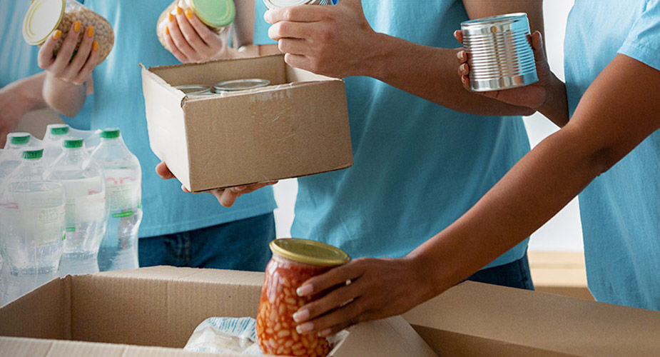 Hands packing canned goods for donation