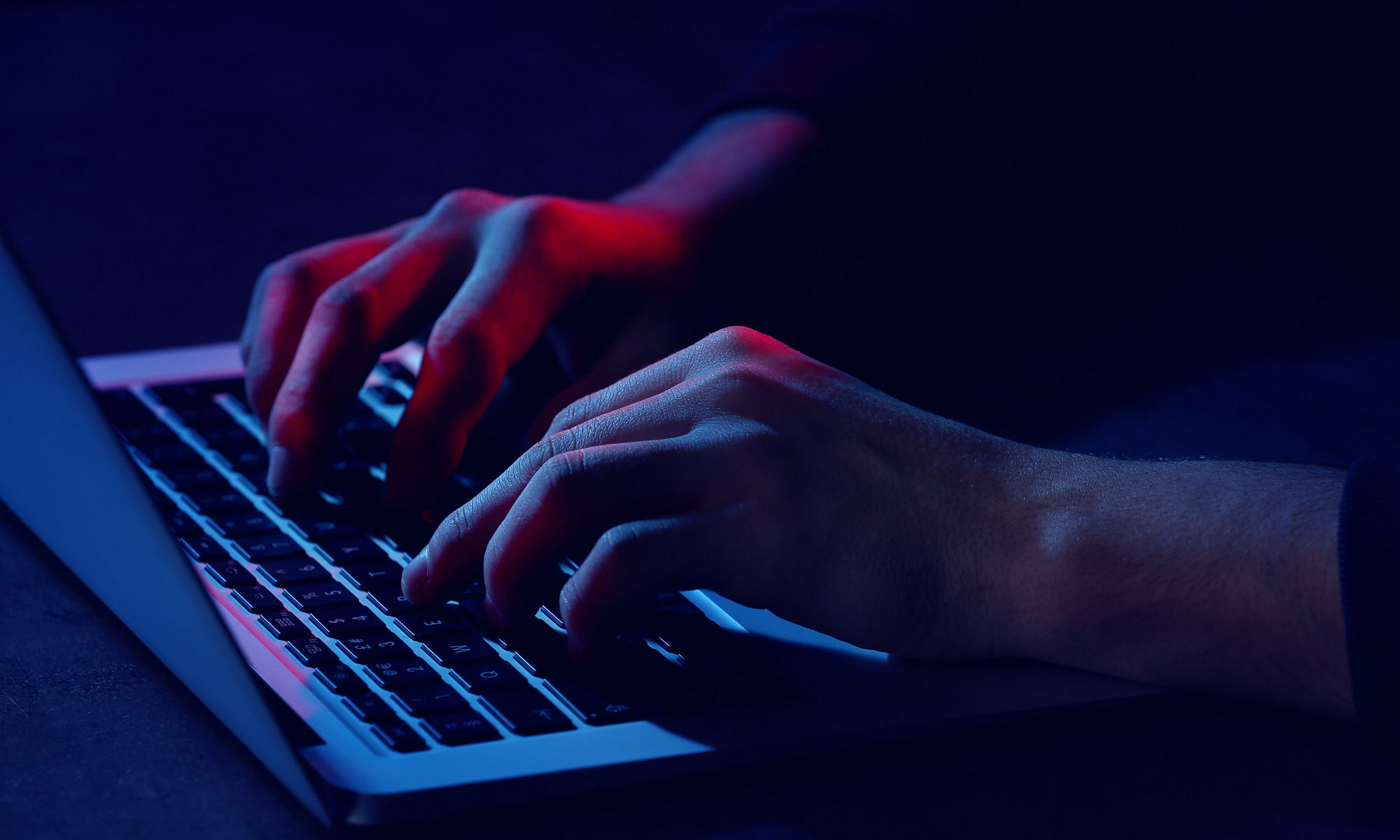 A person typing in the keyboard in dark background