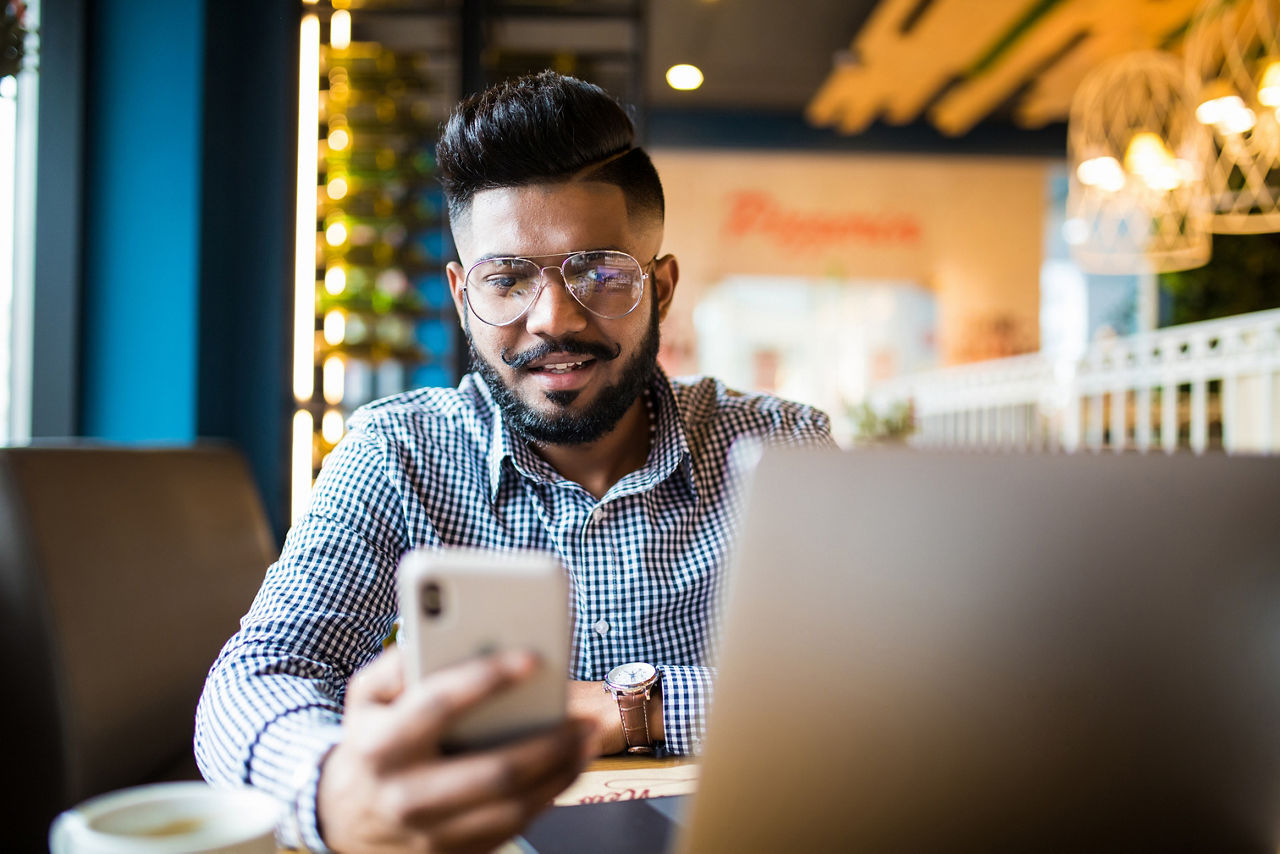 Man looking over a piece of paper while another man observes from his laptop