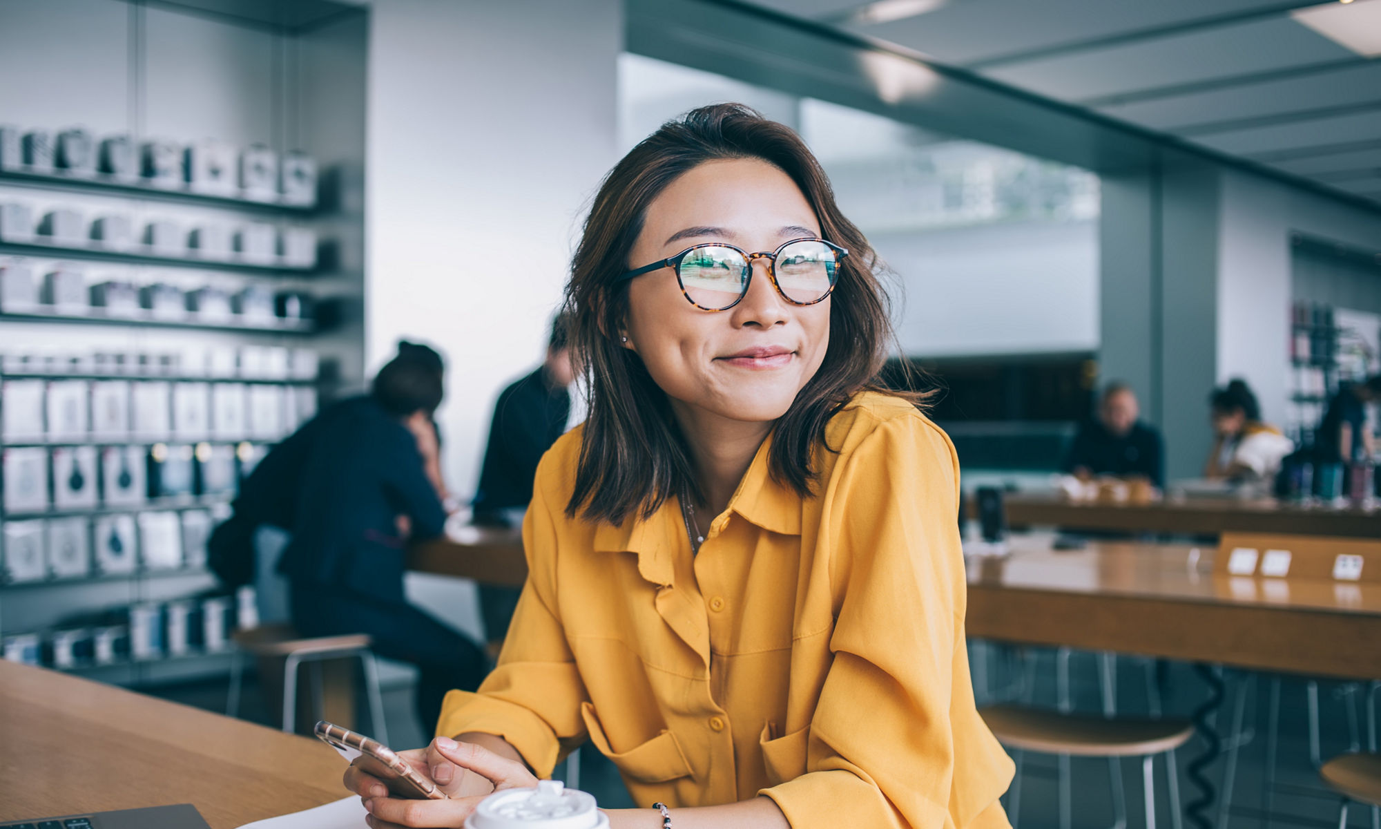 Portrait of cheerful hipster girl in optical spectacles for provide eyes protection looking at camera and smiling during blogging time in university classroom, concept of browsing and networking