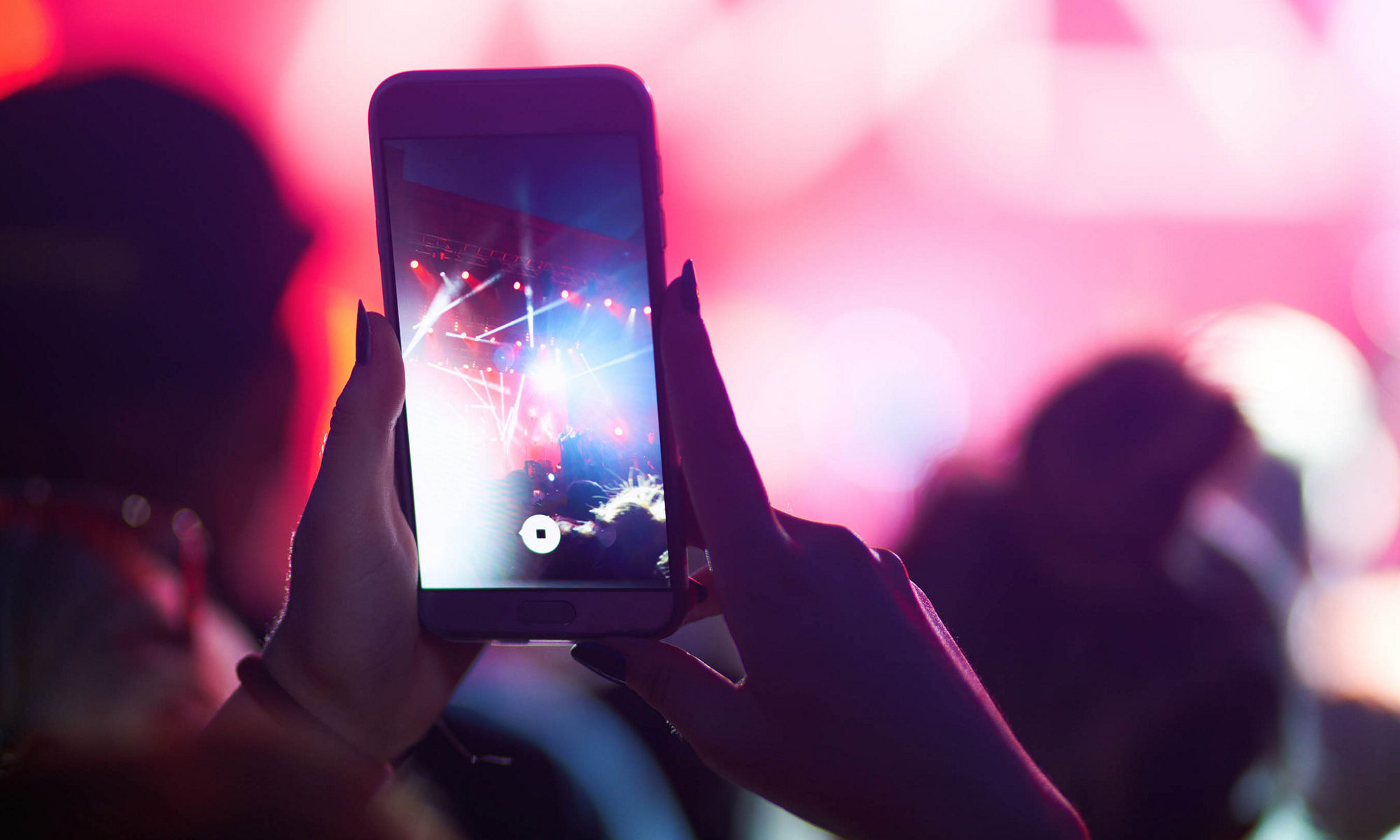 Phone being used at public event in pink hues