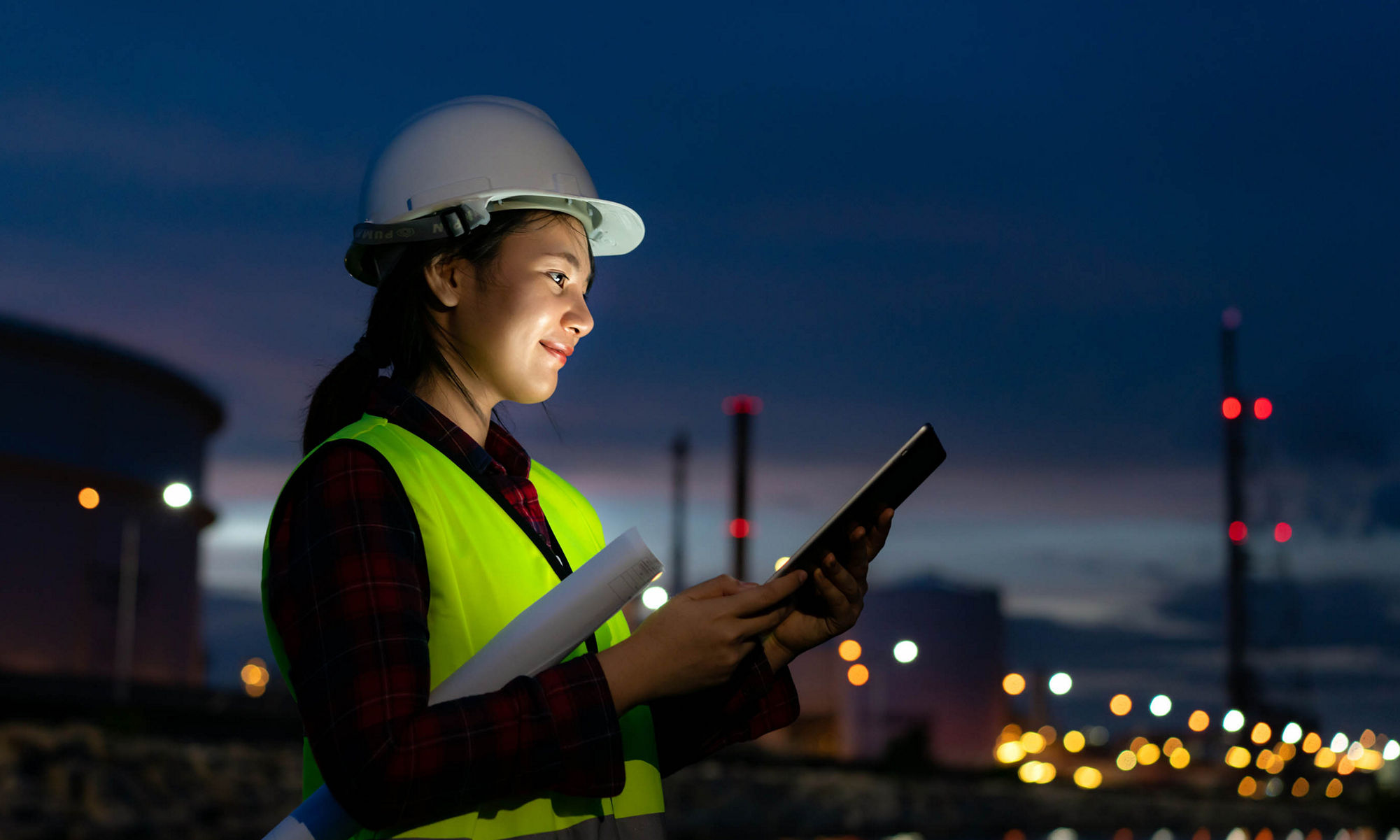 Women wearing helmet holding ipad in hand with city lights in the background