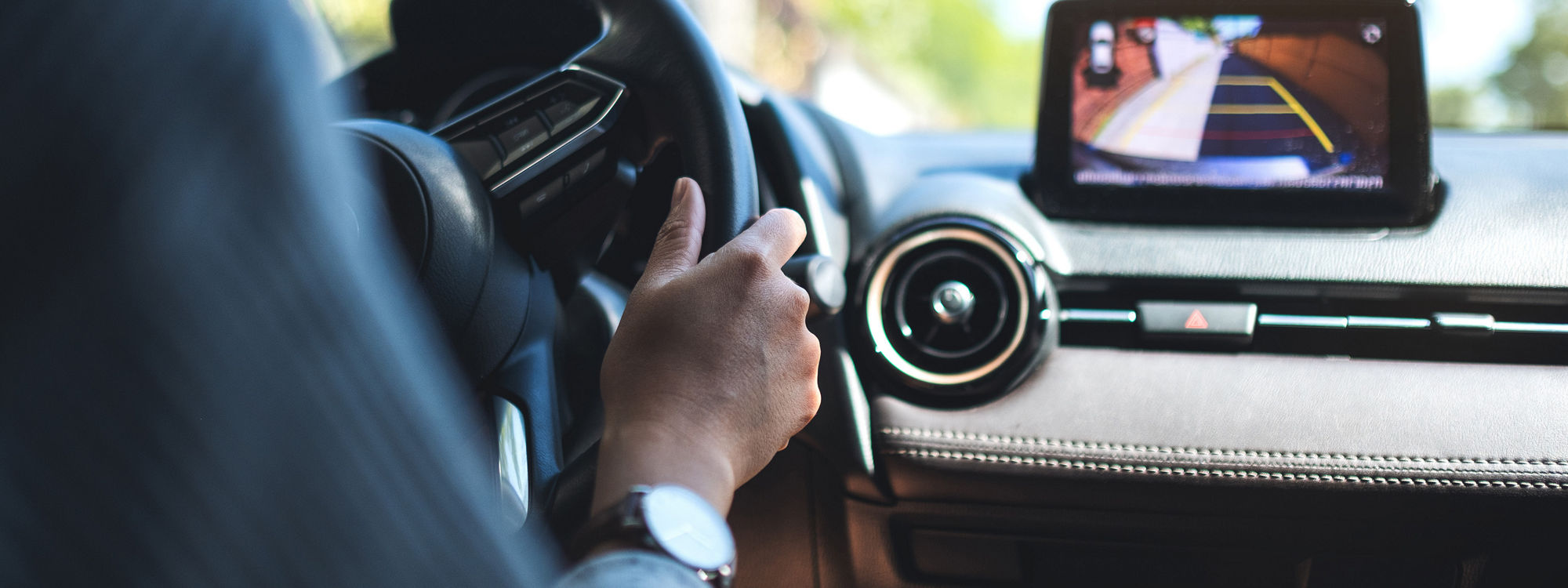 Closeup image of a woman holding steering wheel while driving a car on the road