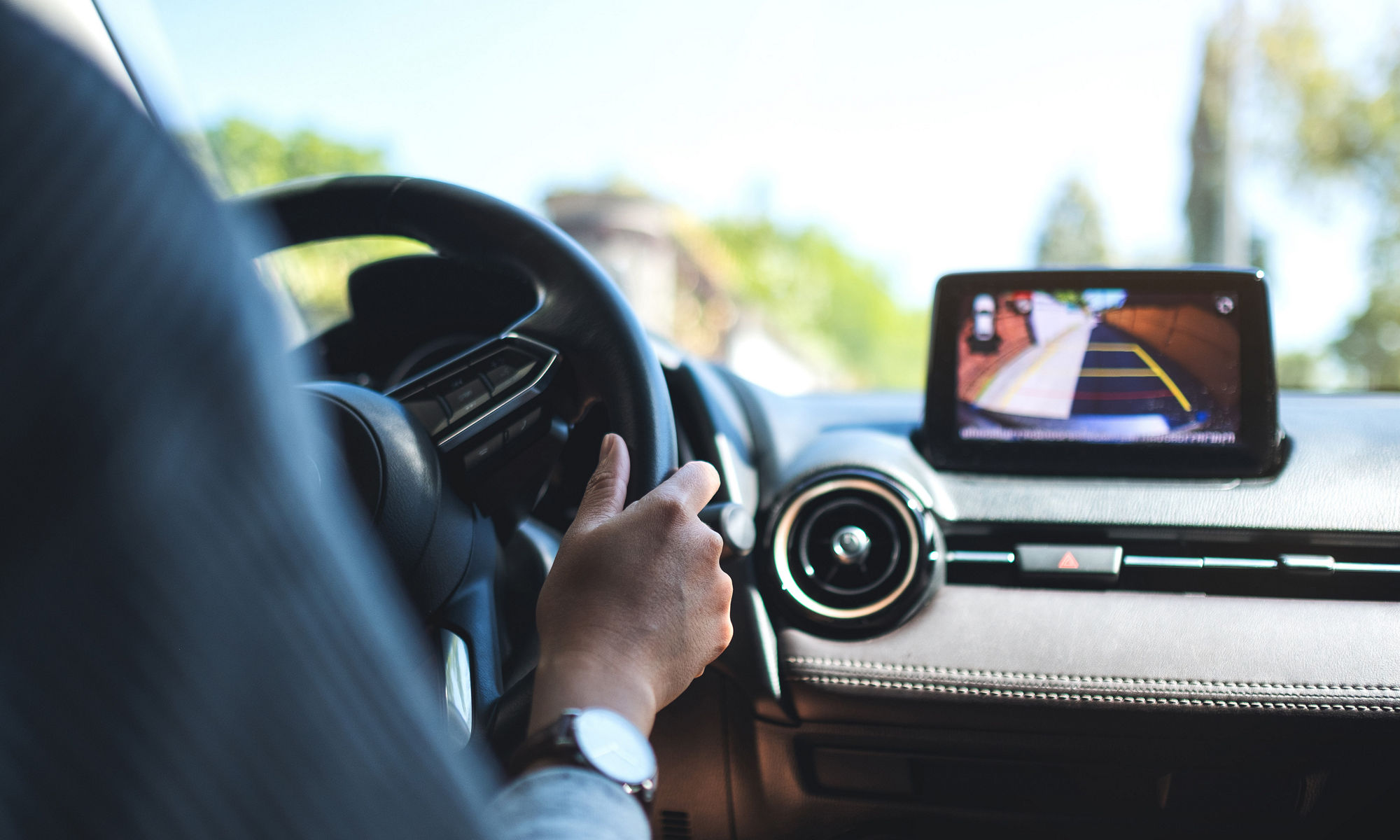 Closeup image of a woman holding steering wheel while driving a car on the road