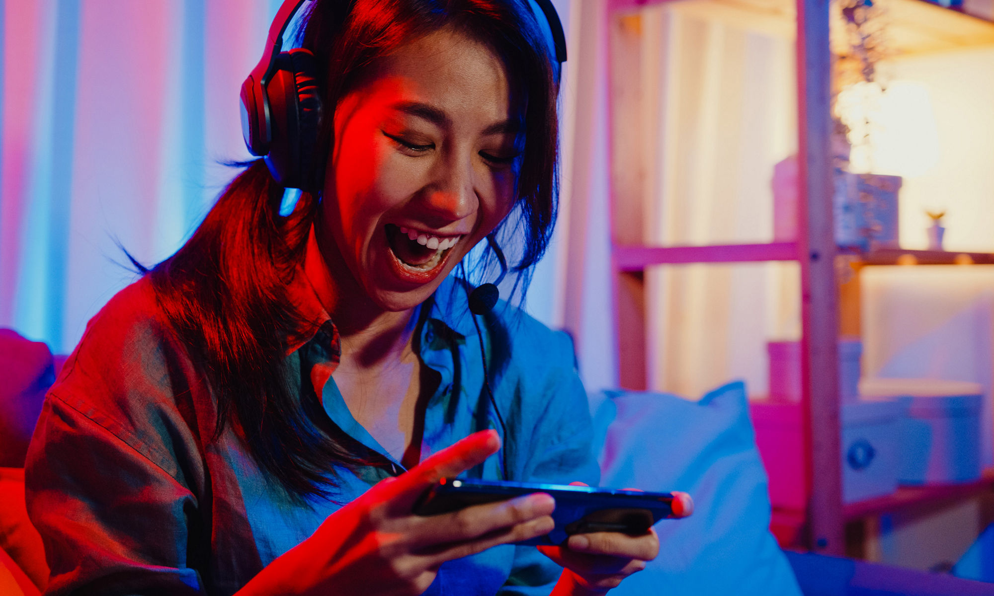 ヘッドフォンをつけてスマートフォンでゲームをプレイしている少女