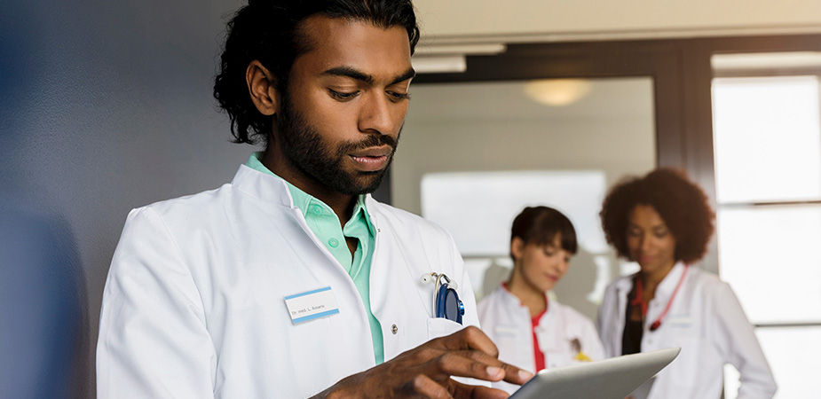 Male doctor of color reviewing a document with two doctors in the background