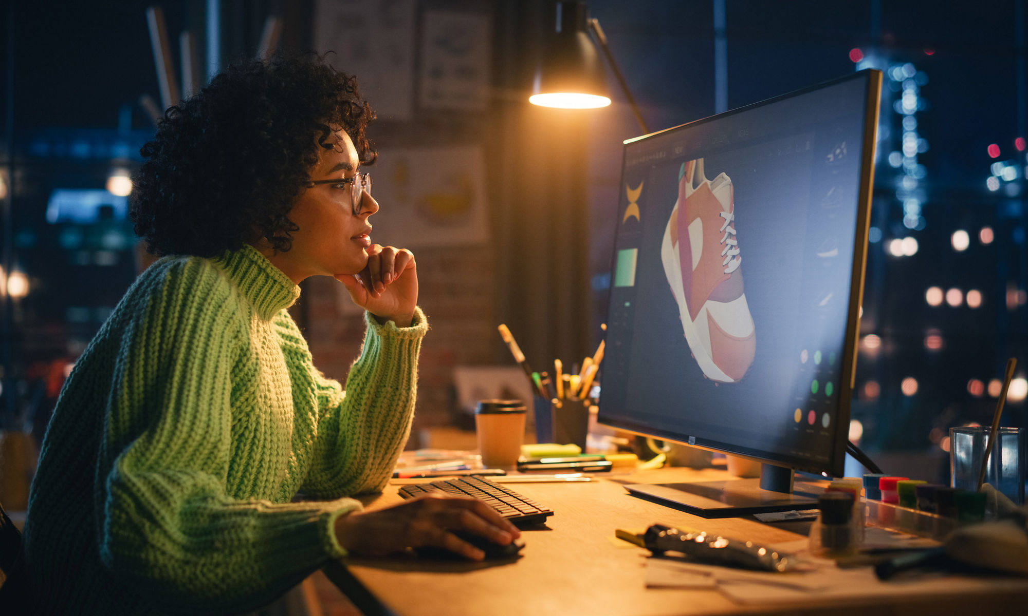 Woman in green sweater in front of monitor