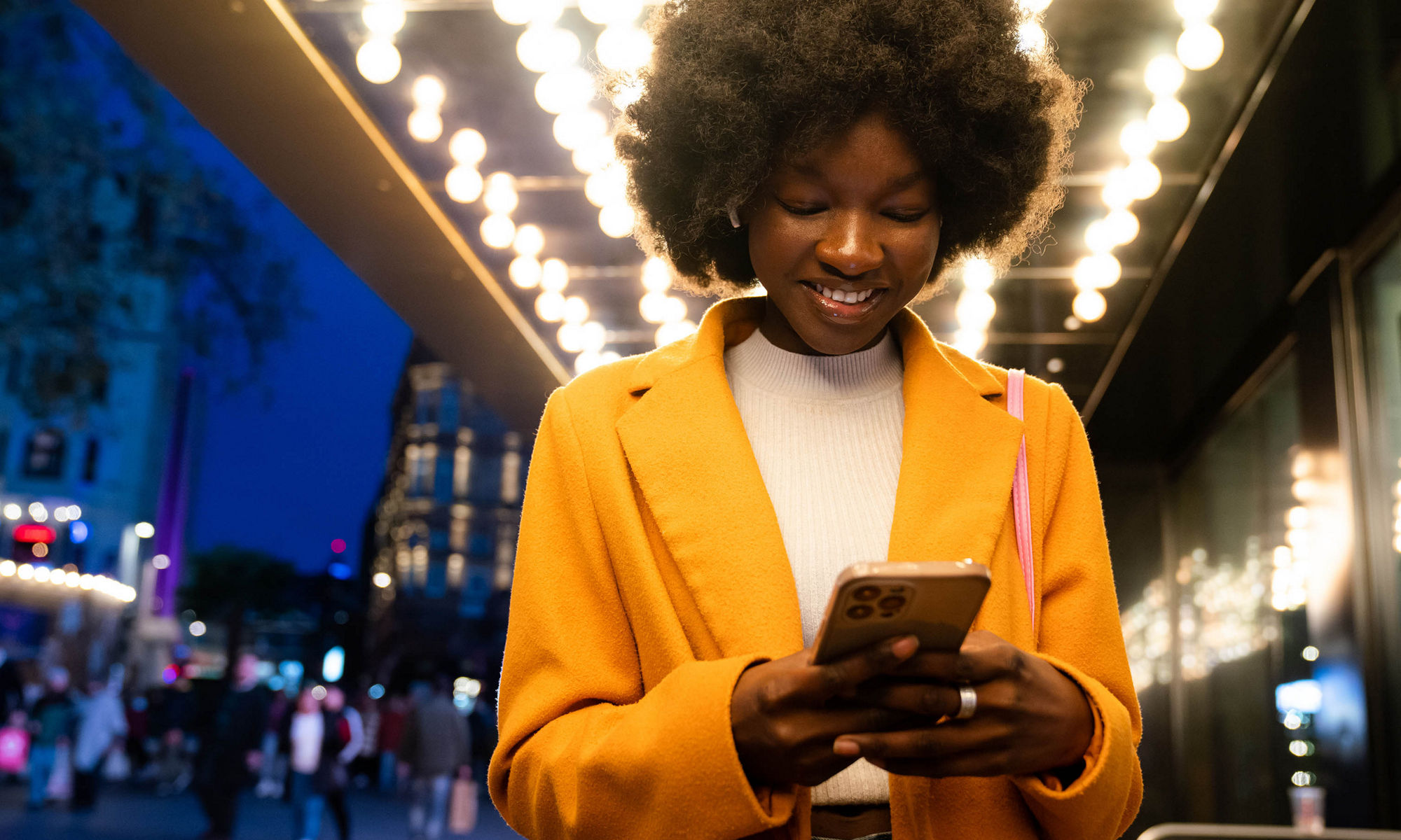 Women looking at the mobile phone in a hallway with lights lit in the background