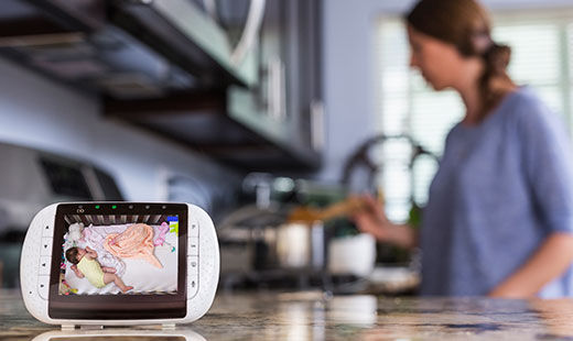 a baby monitor in a kitchen while a mother cooks in the background 