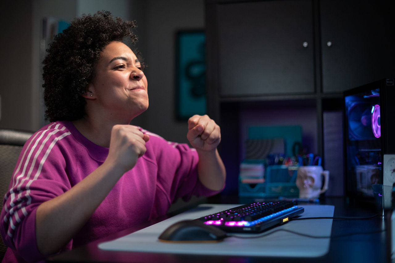 Young woman sitting in front of computer with an excited, pleased expression.