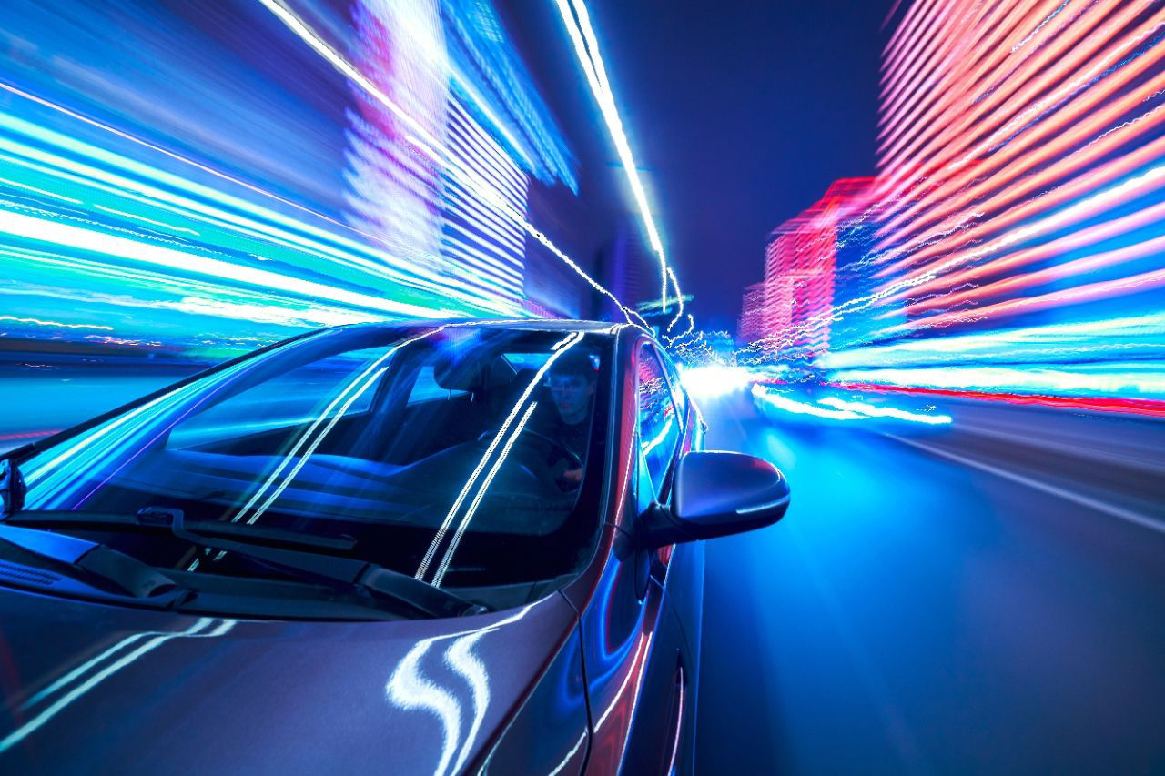 car speeding through city street, streaks of light from buildings