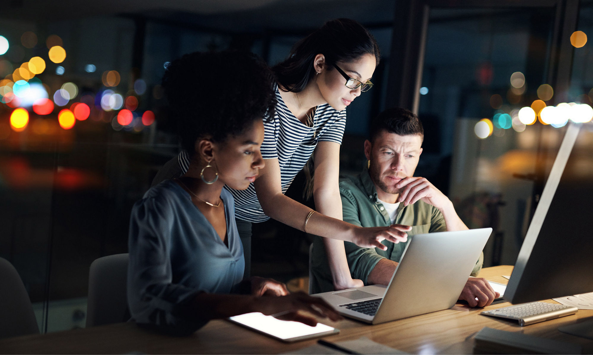 three individuals around a laptop looking at screen