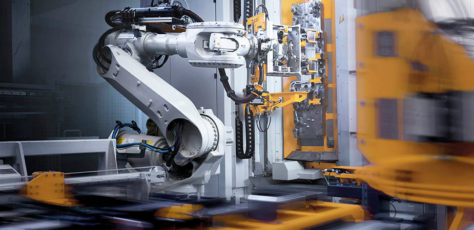 A heavy-duty industrial robotic arm operating machinery on a factory floor.