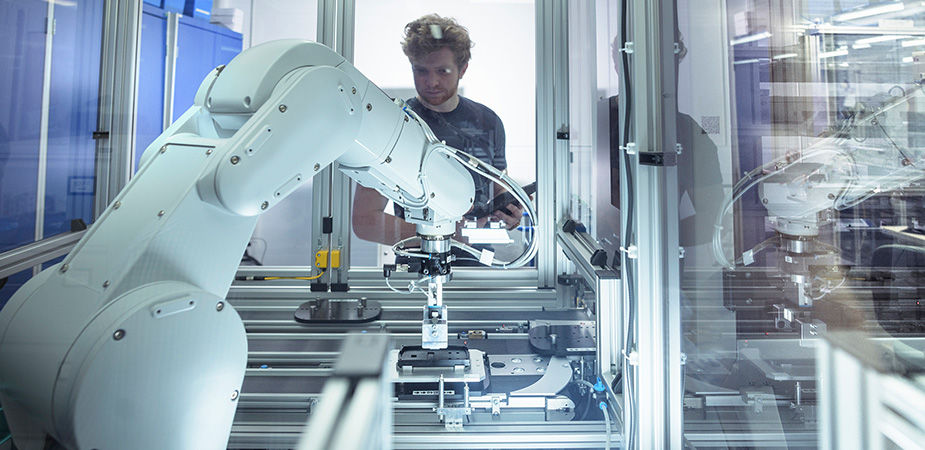 A person working beside a collaborative robotic arm on an automated production line.