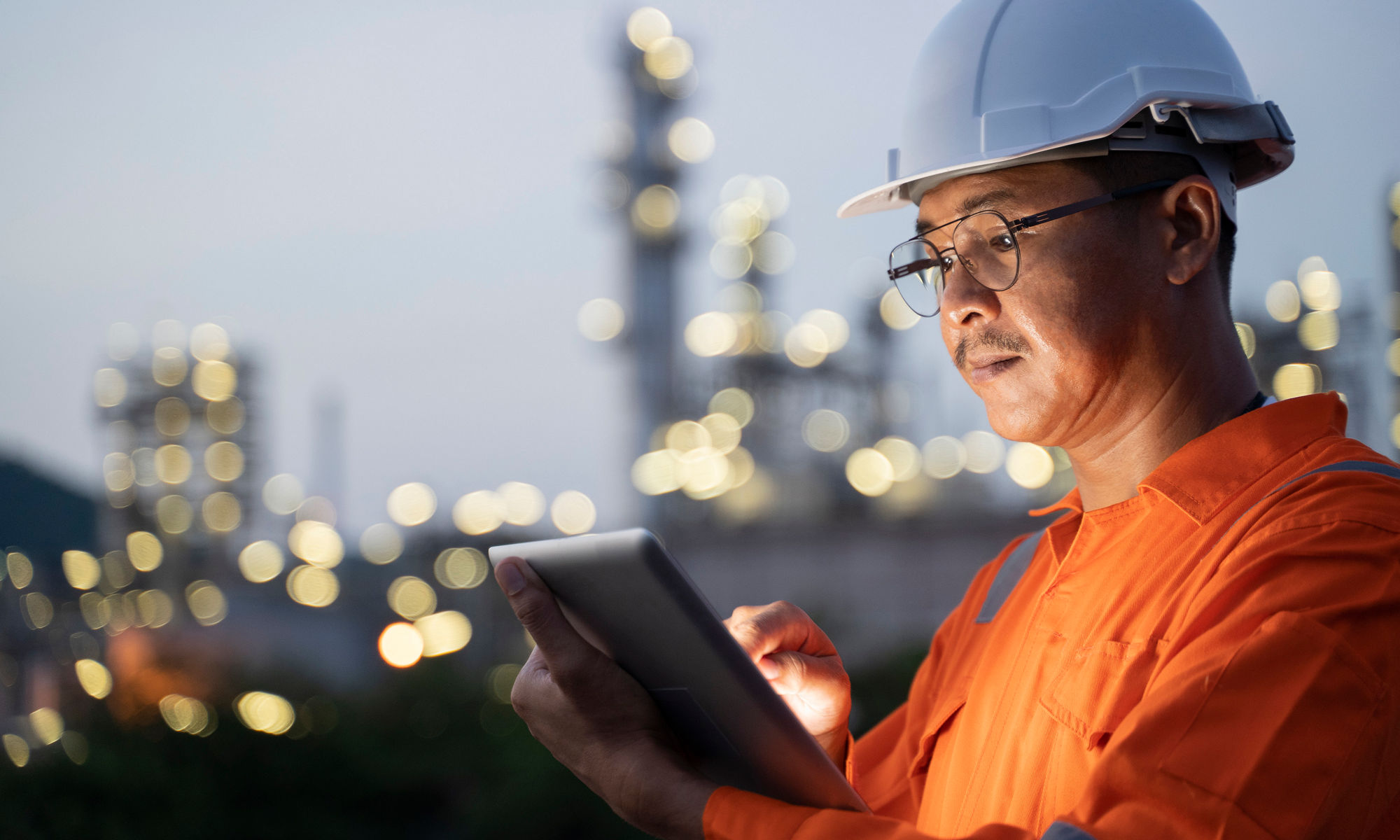 Engineer checking on a tablet with a factory plant setting