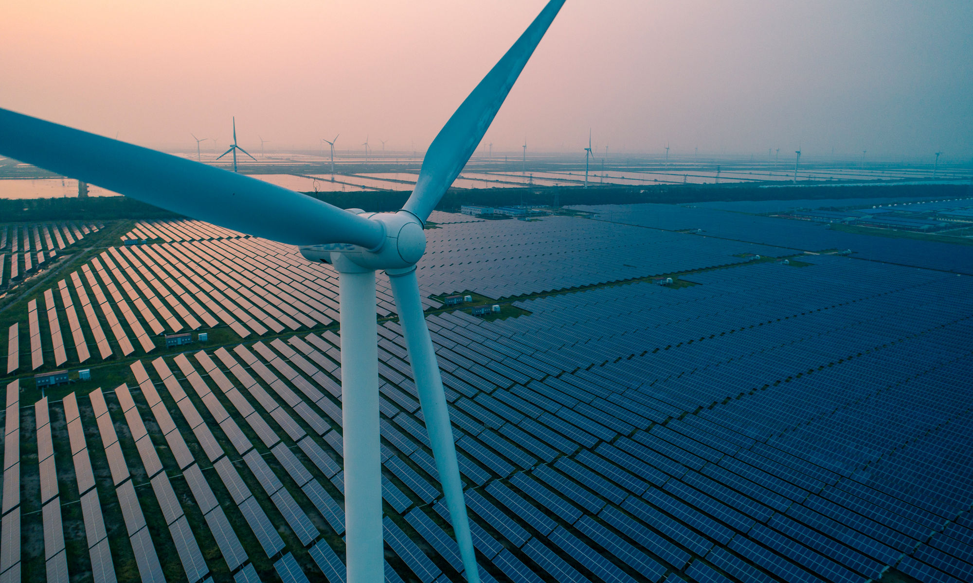 Wind turbine with a solar farm behind it