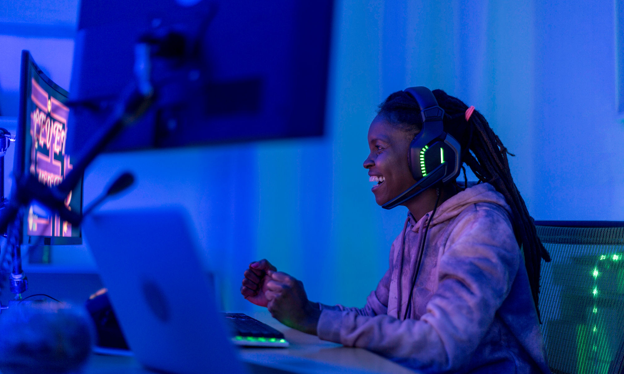 young woman gamer wearing headphones while playing on a pc