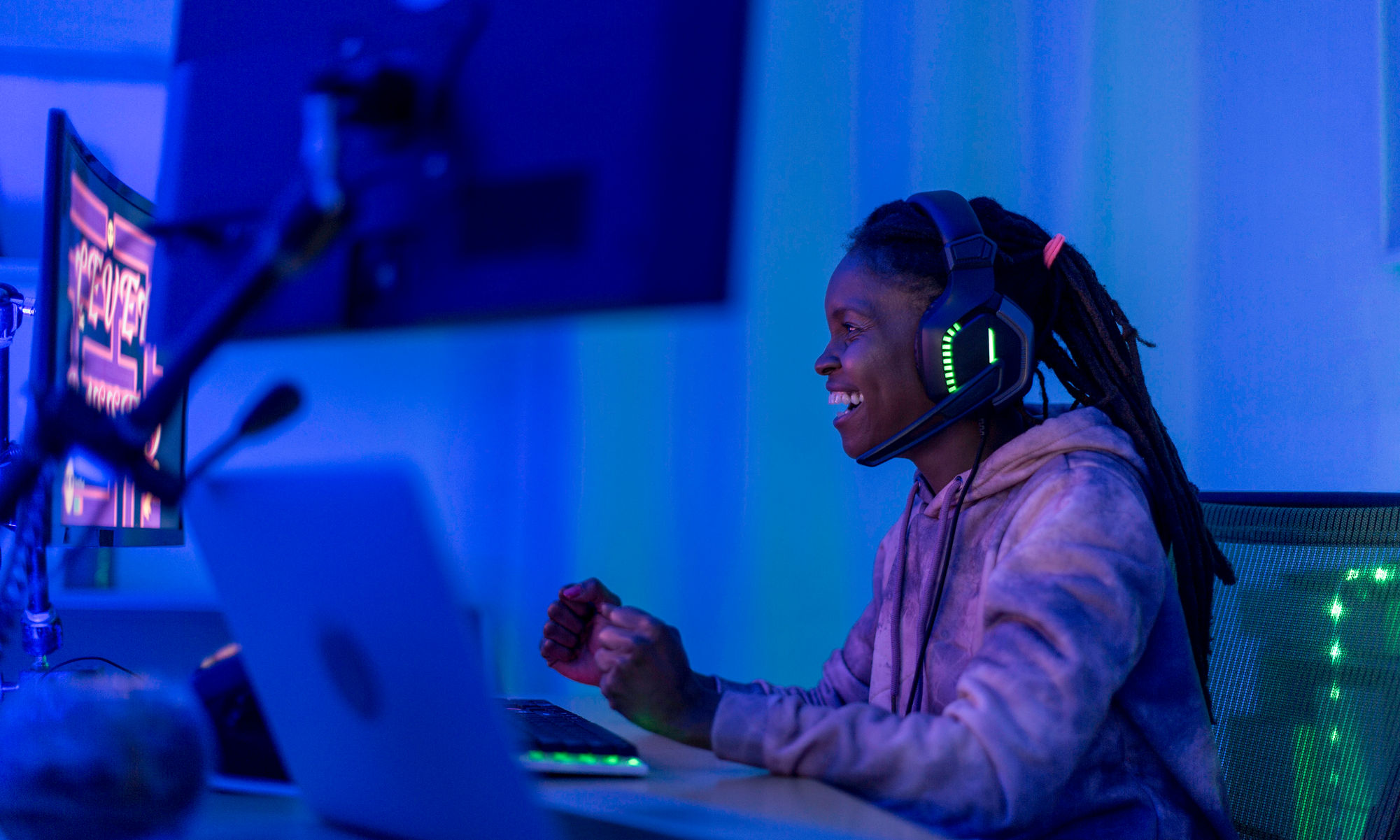 young woman gamer wearing headphones while playing on a pc
