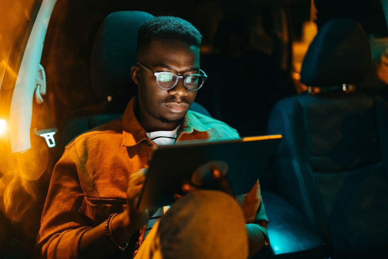 Handsome young businessman using digital tablet in car