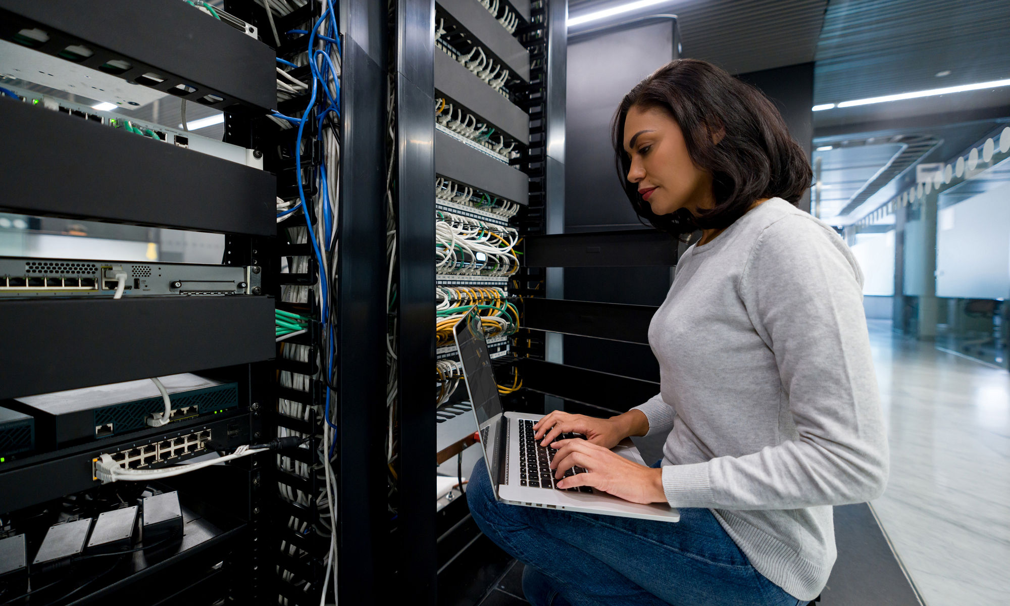 Female IT support technician fixing a network server at an office - technology concepts