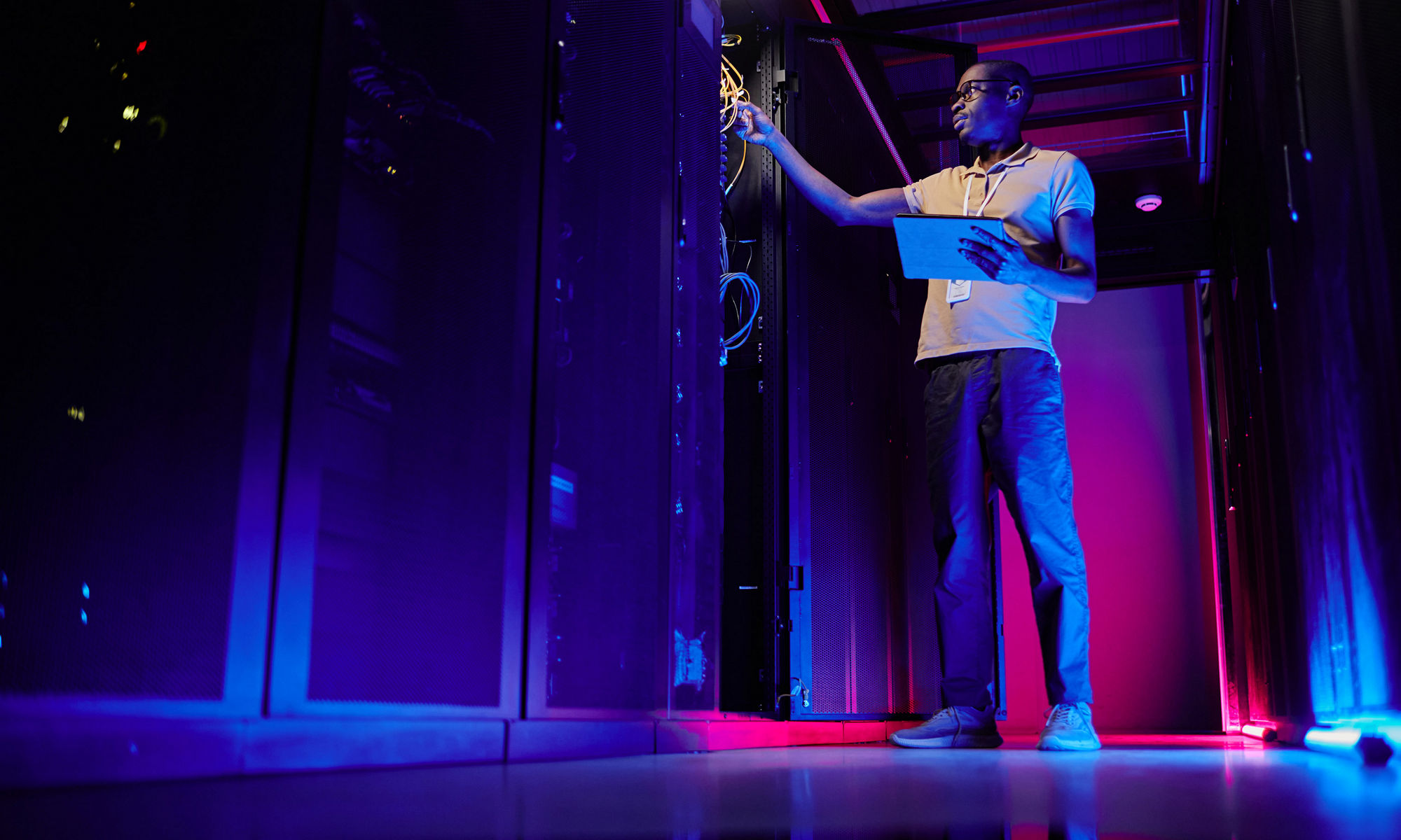 Man standing in data center with purple lights glowing