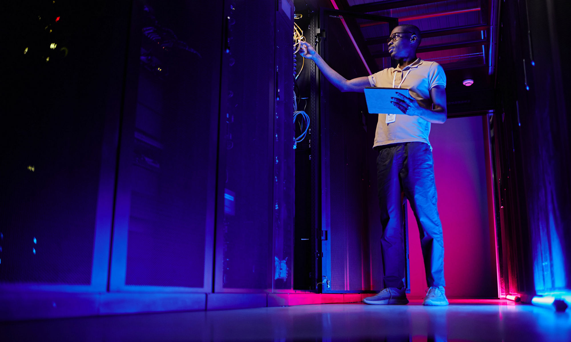 man standing in data center with purple lights glowing