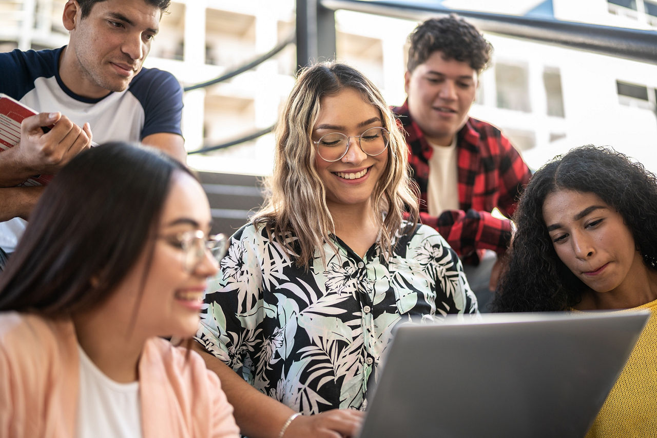 Group of students gathered around a laptop