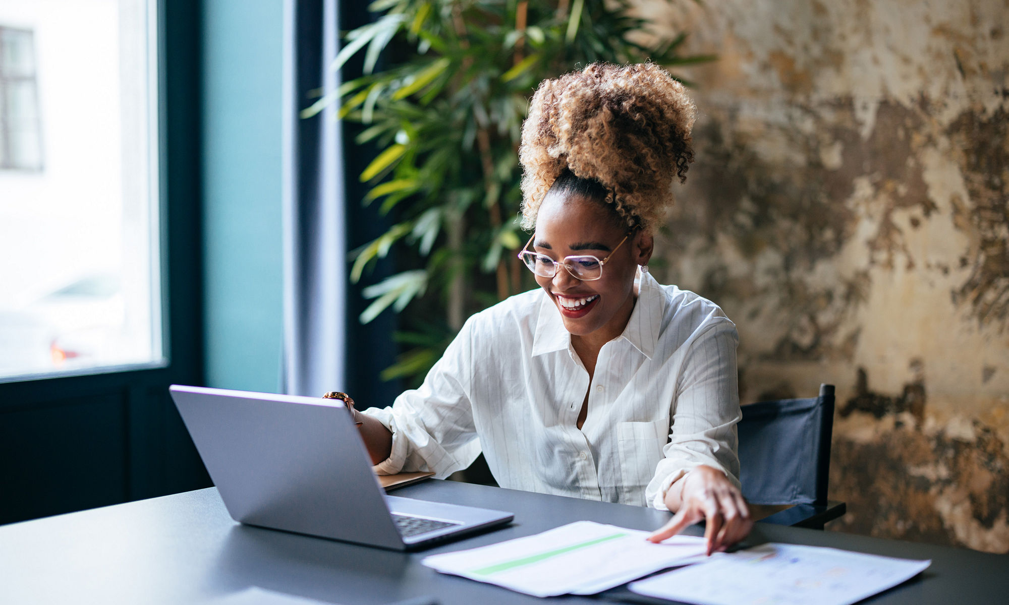 Women looking at the papers on the table with a laptop infront of her