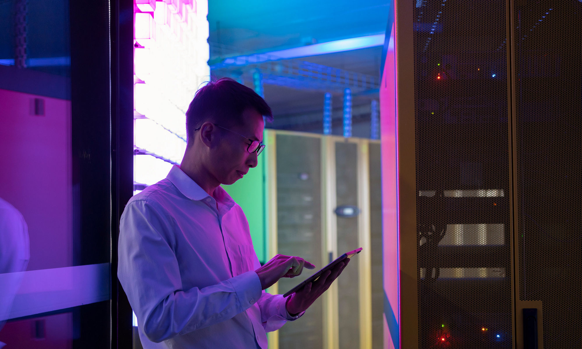 Man standing in data center typing on mobile device