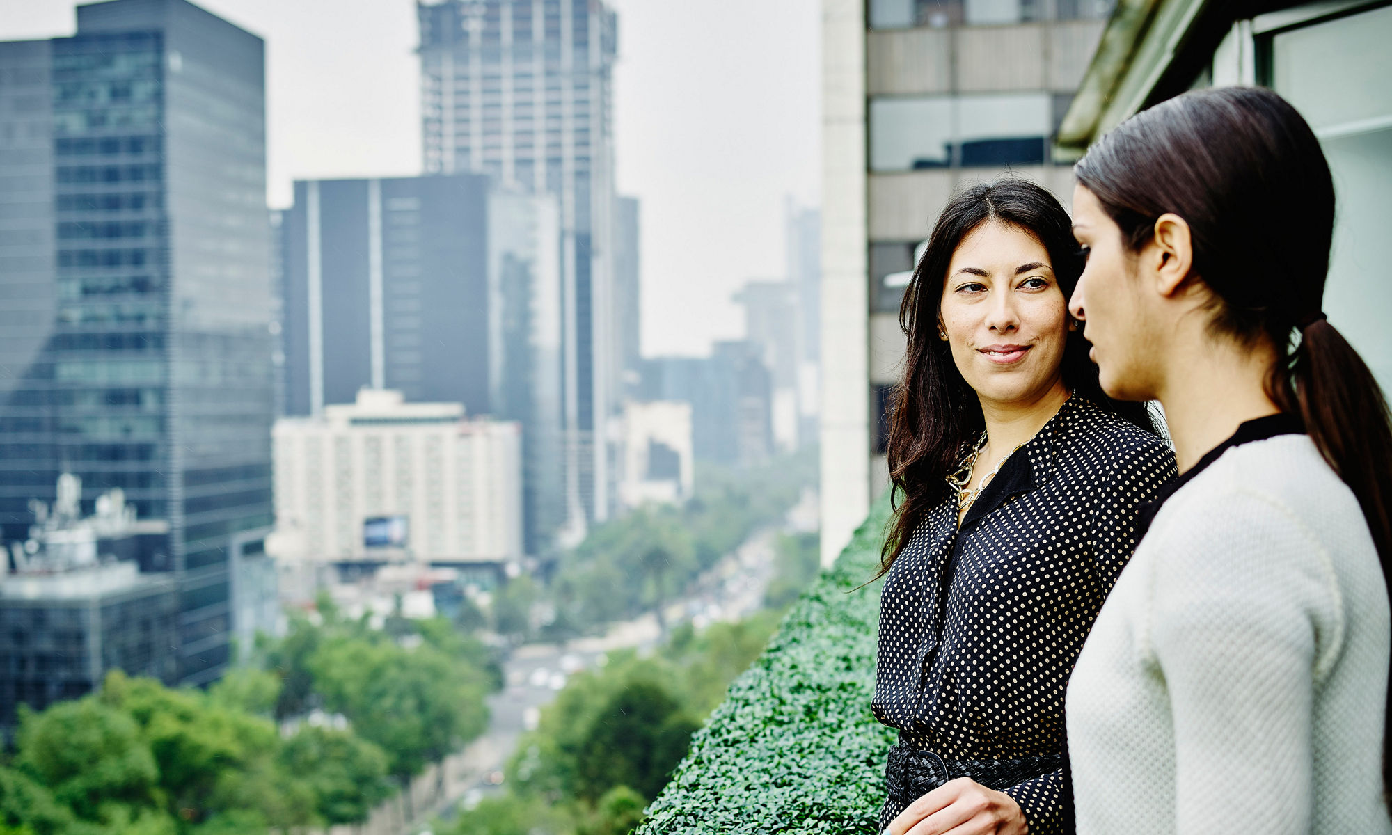 two women talking on the balcony of high raise building