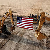 An American flag suspended between construction equipment. 