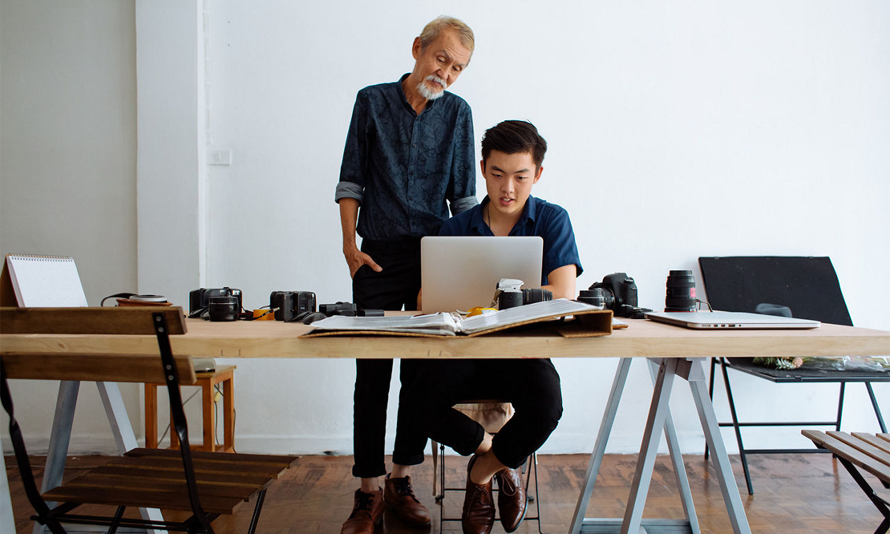 Two people of color reading a resume on a laptop.