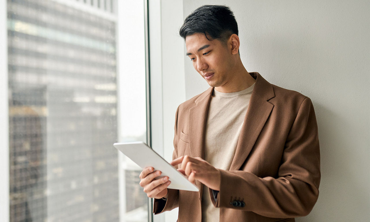 A seated young man reading a computer screen in a work environment