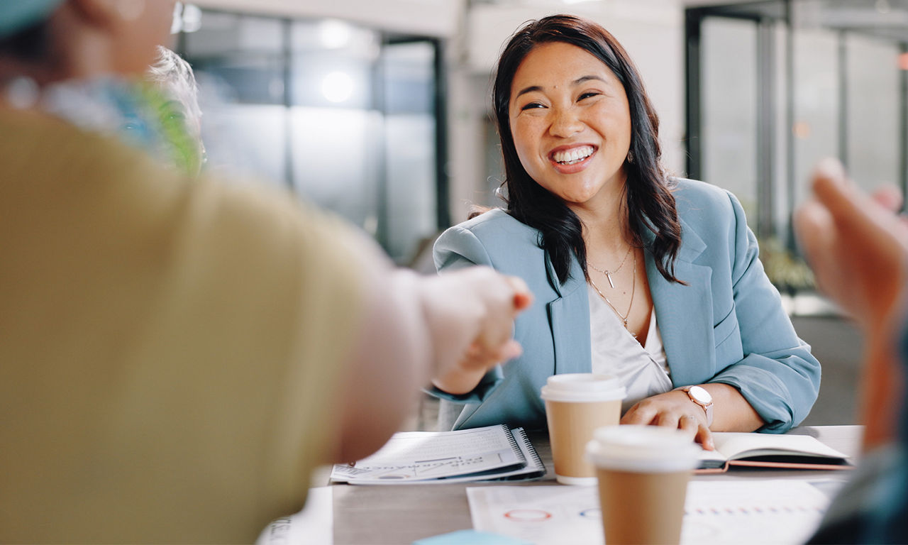 A smiling woman with an outreached hand