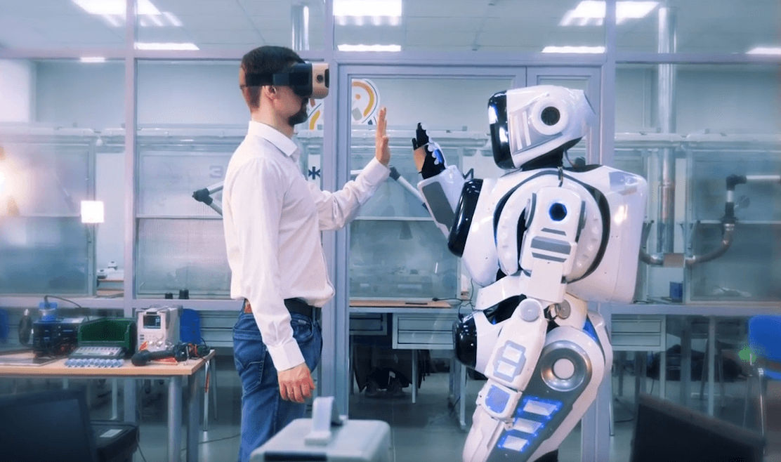 A person wearing a virtual reality headset interacting with a human-scale AI robot.
