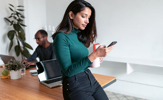 Woman leaning on table typing on mobile device