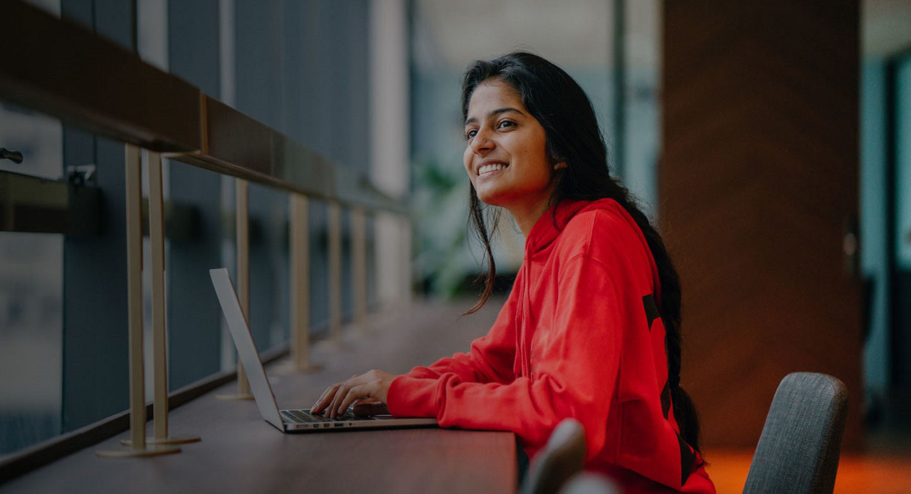 young woman smiling typing on laptop