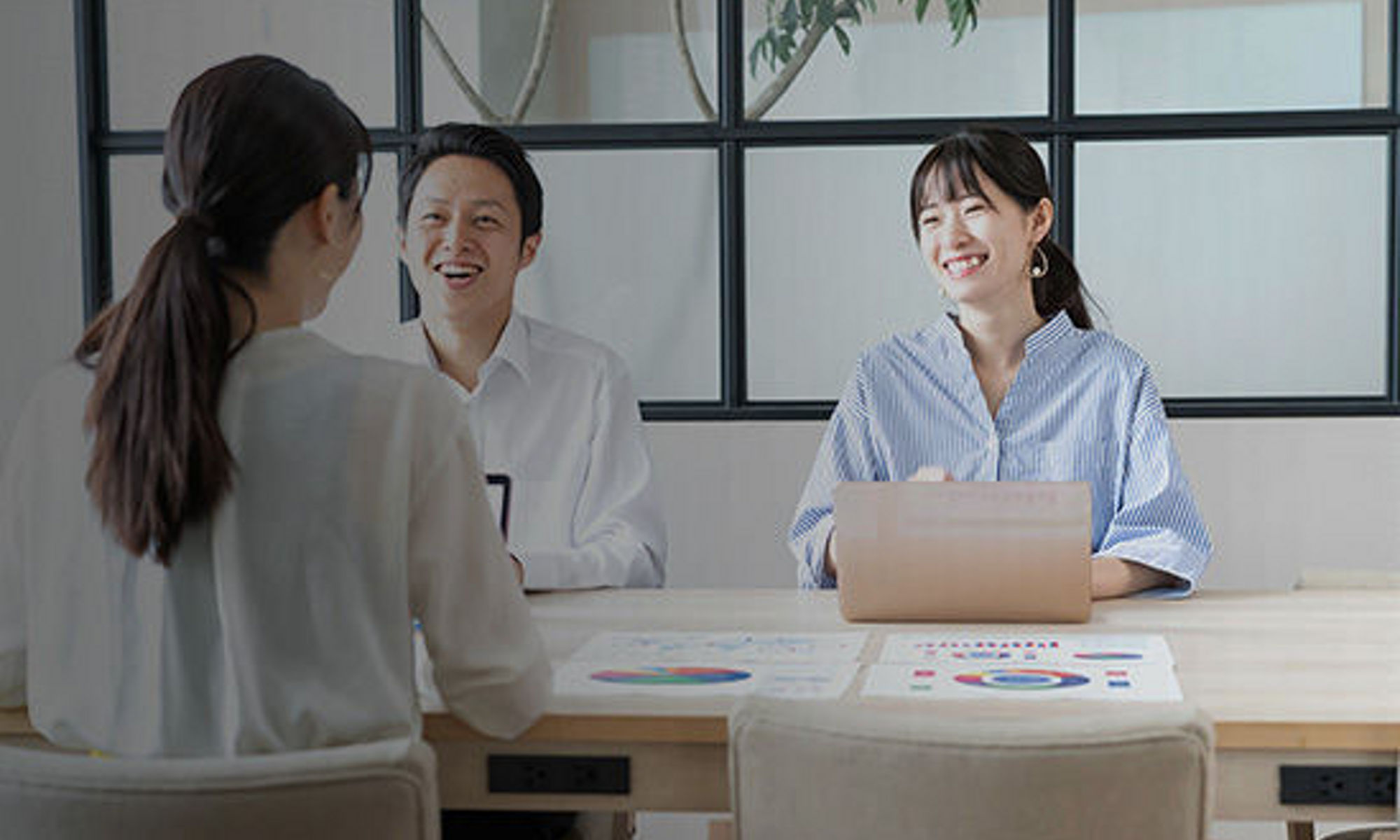 Groupd of people sitting around the desk with laptop infront