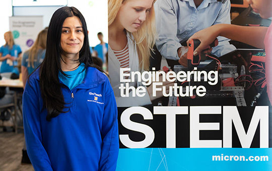 Woman of color working Posing infront of the banner that says engineering the future STEM