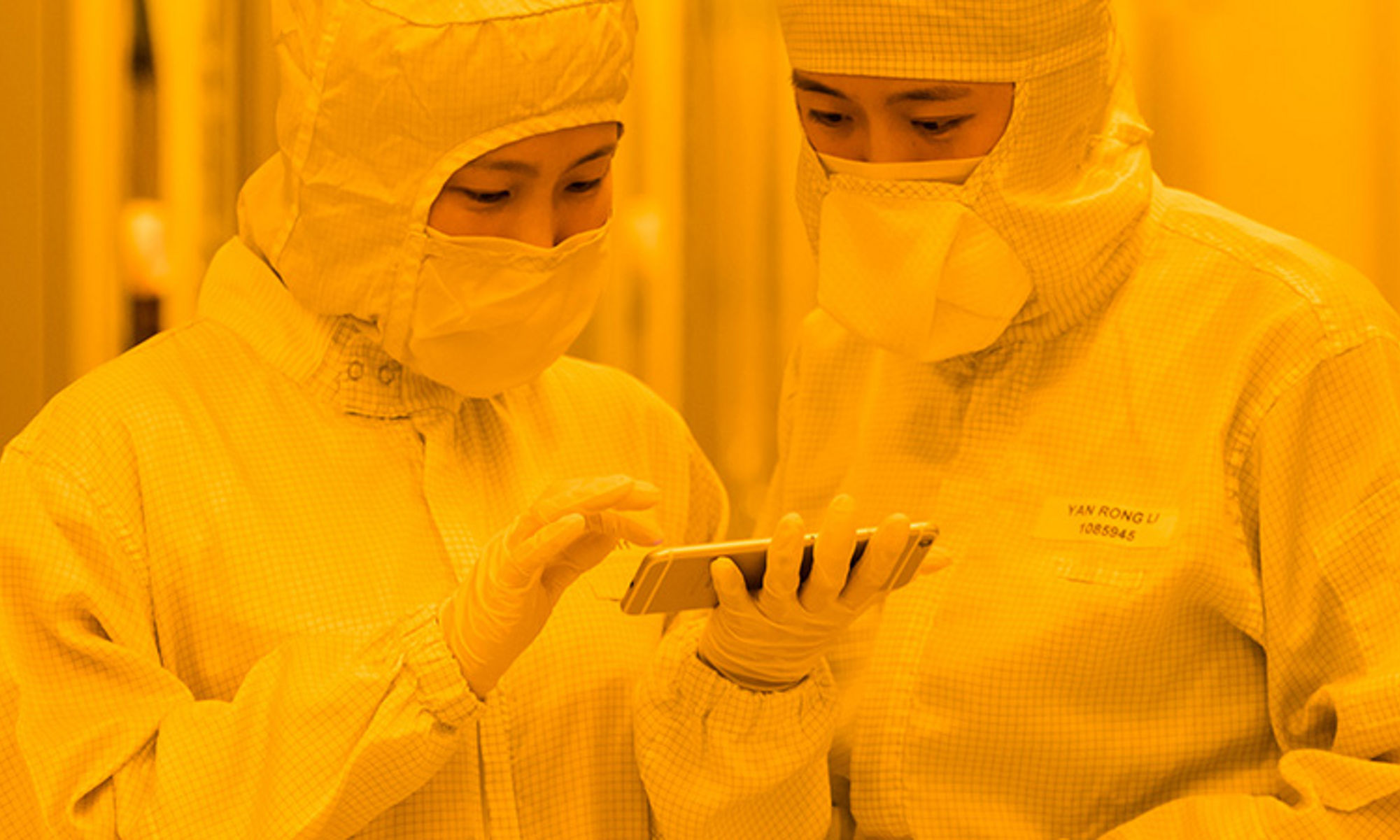 Two workers in clean-room attire intently reviewing specs