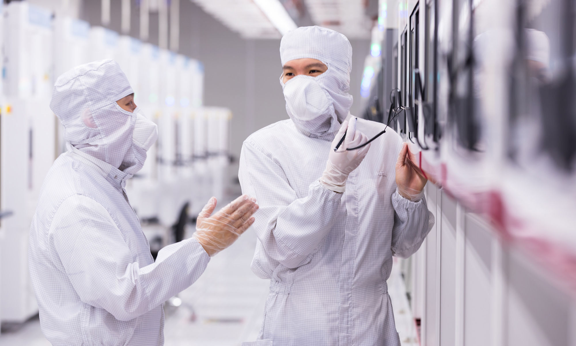 Two employees in bunny suits in a fabrication plant