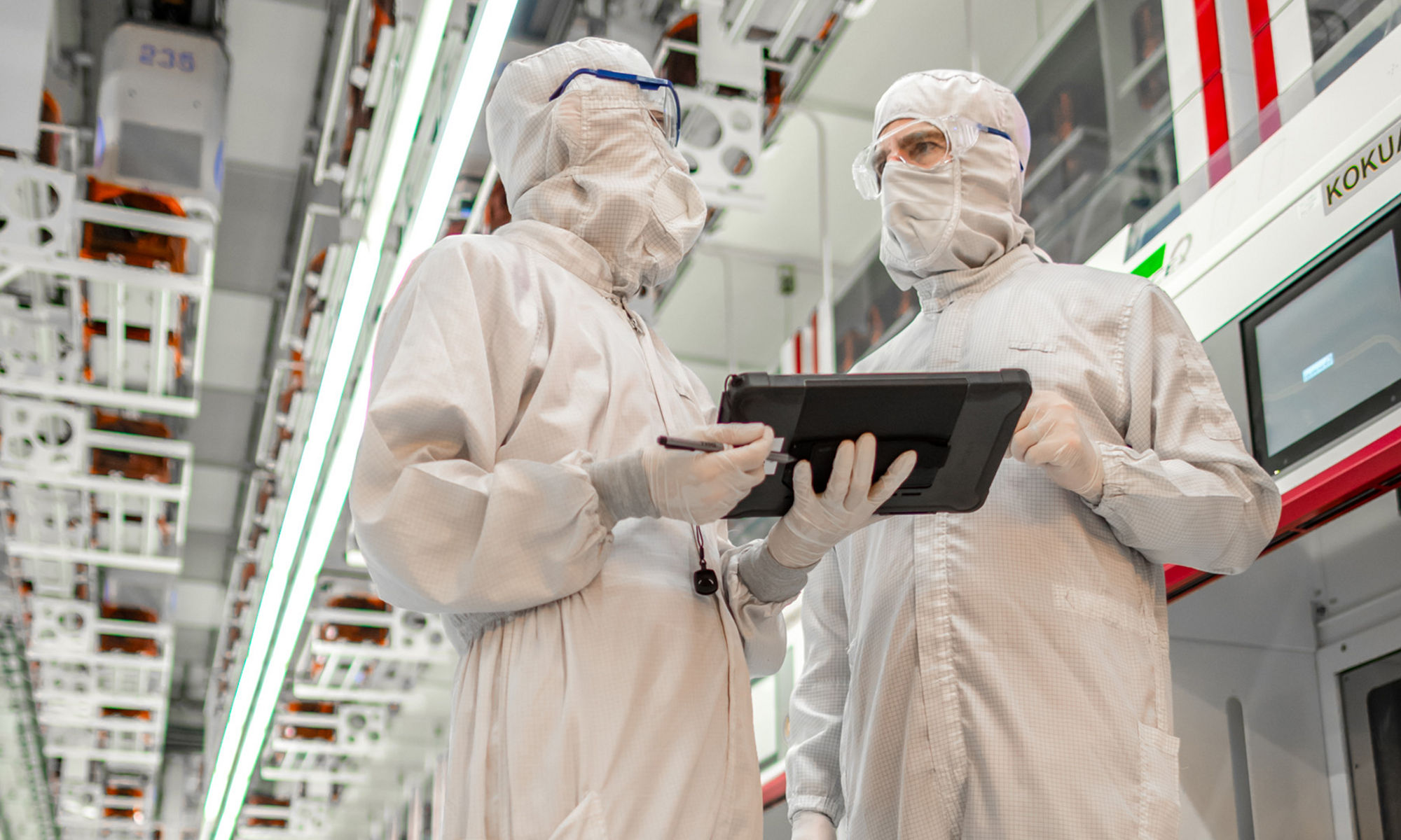 Two Micron manufactuing employees wearing cleansuits in a production environment