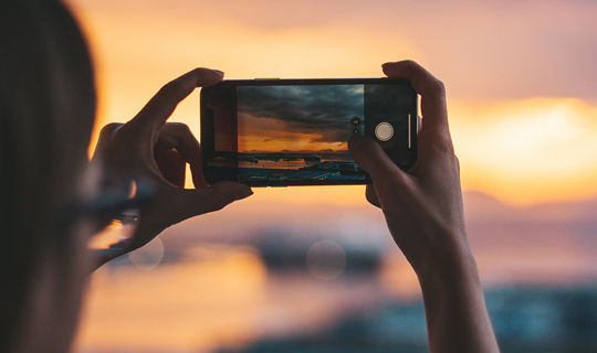 Woman holding smart phone taking a photo